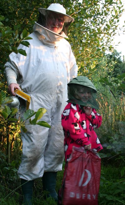 Bob McCutcheon visiting his bees with his granddaughter Asha